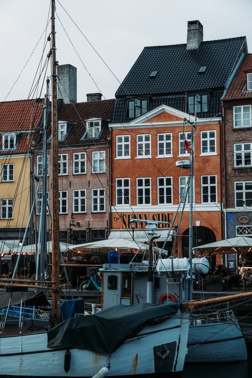 Free Charming colorful buildings line the canal in Copenhagen, Denmark with a classic boat in the foreground. Stock Photo
