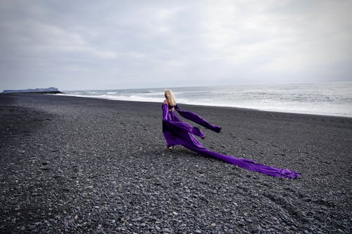 A woman in a purple dress is walking on the beach