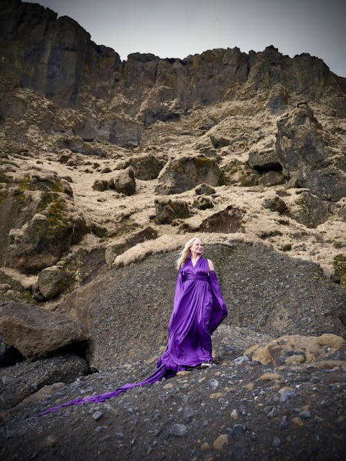 A woman in a purple dress standing on a rocky hill