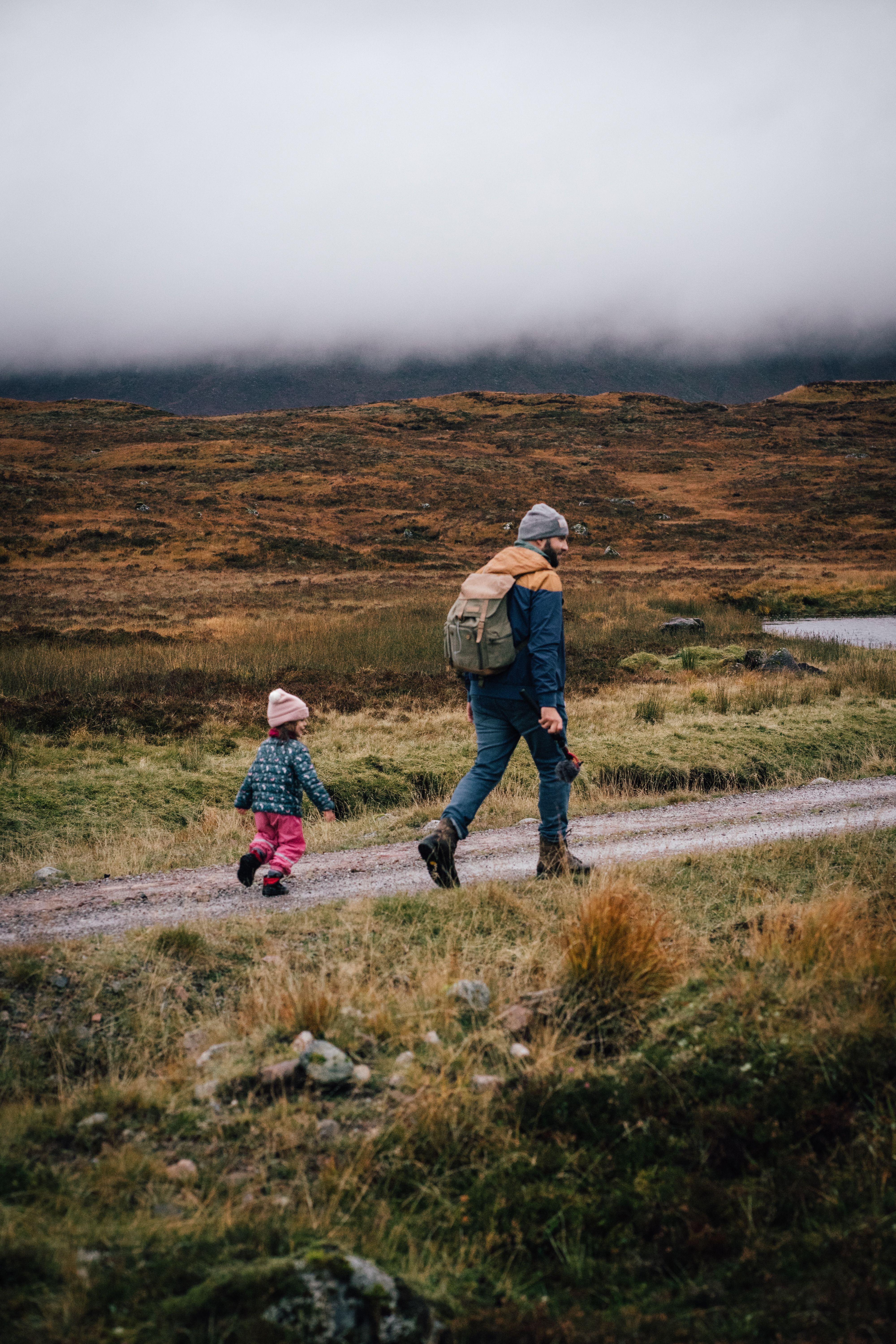 A father and daughter enjoy a scenic hike on a trail in autumn.