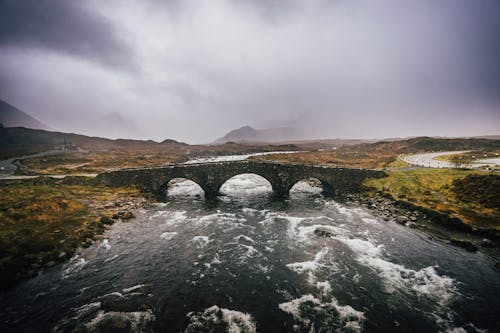 A stone bridge over a river under a cloudy sky