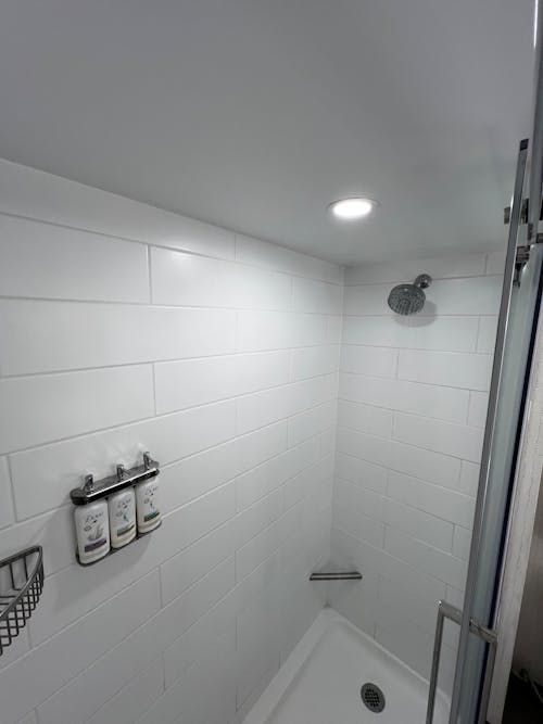 A white shower with a light above it