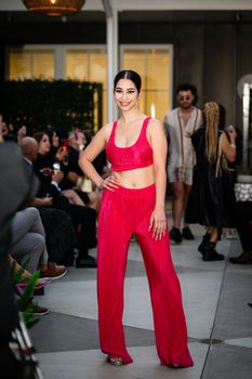 Smiling woman in pink attire standing confidently at a stylish urban event.