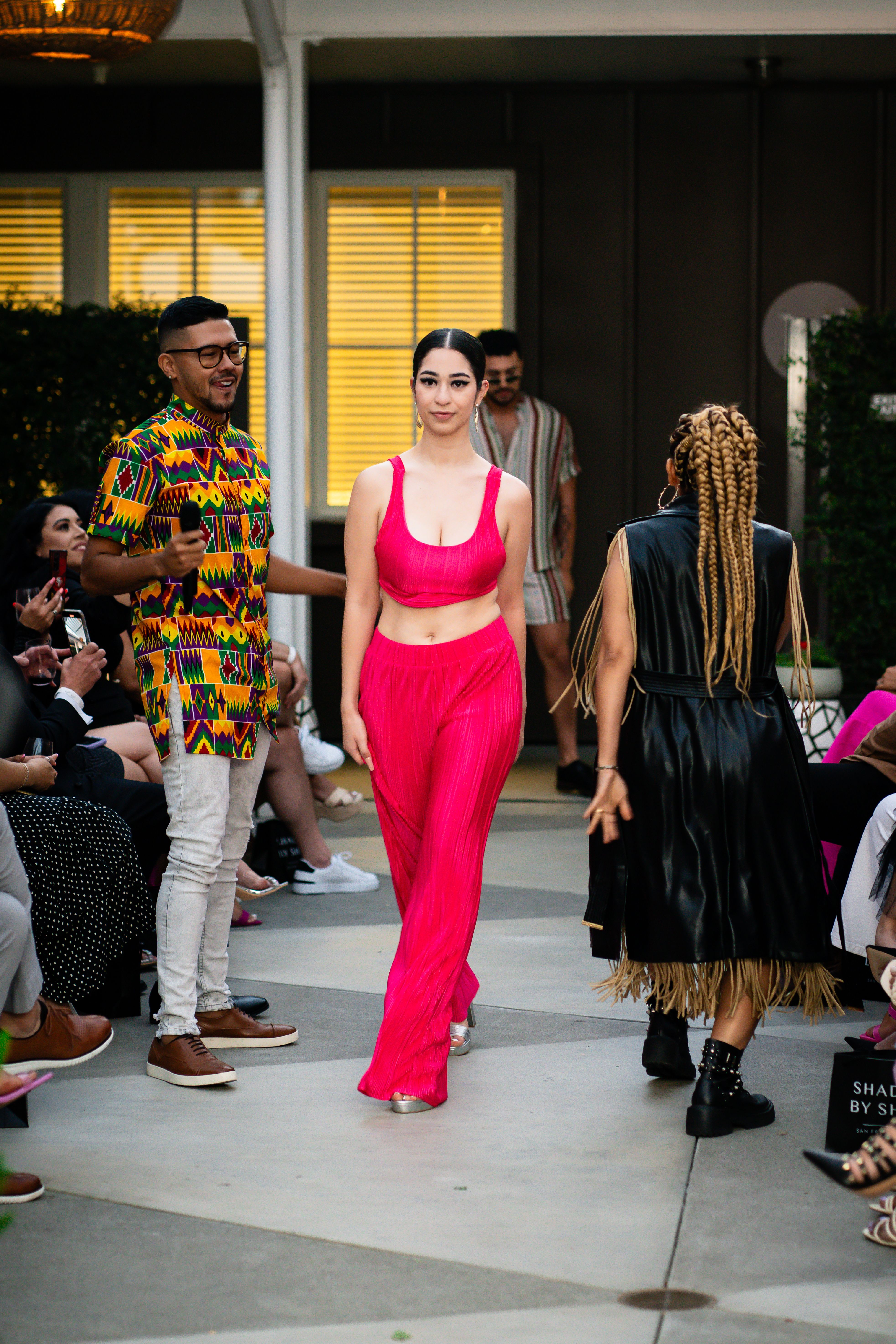 Dynamic fashion show featuring colorful outfits and diverse models on a lively catwalk.