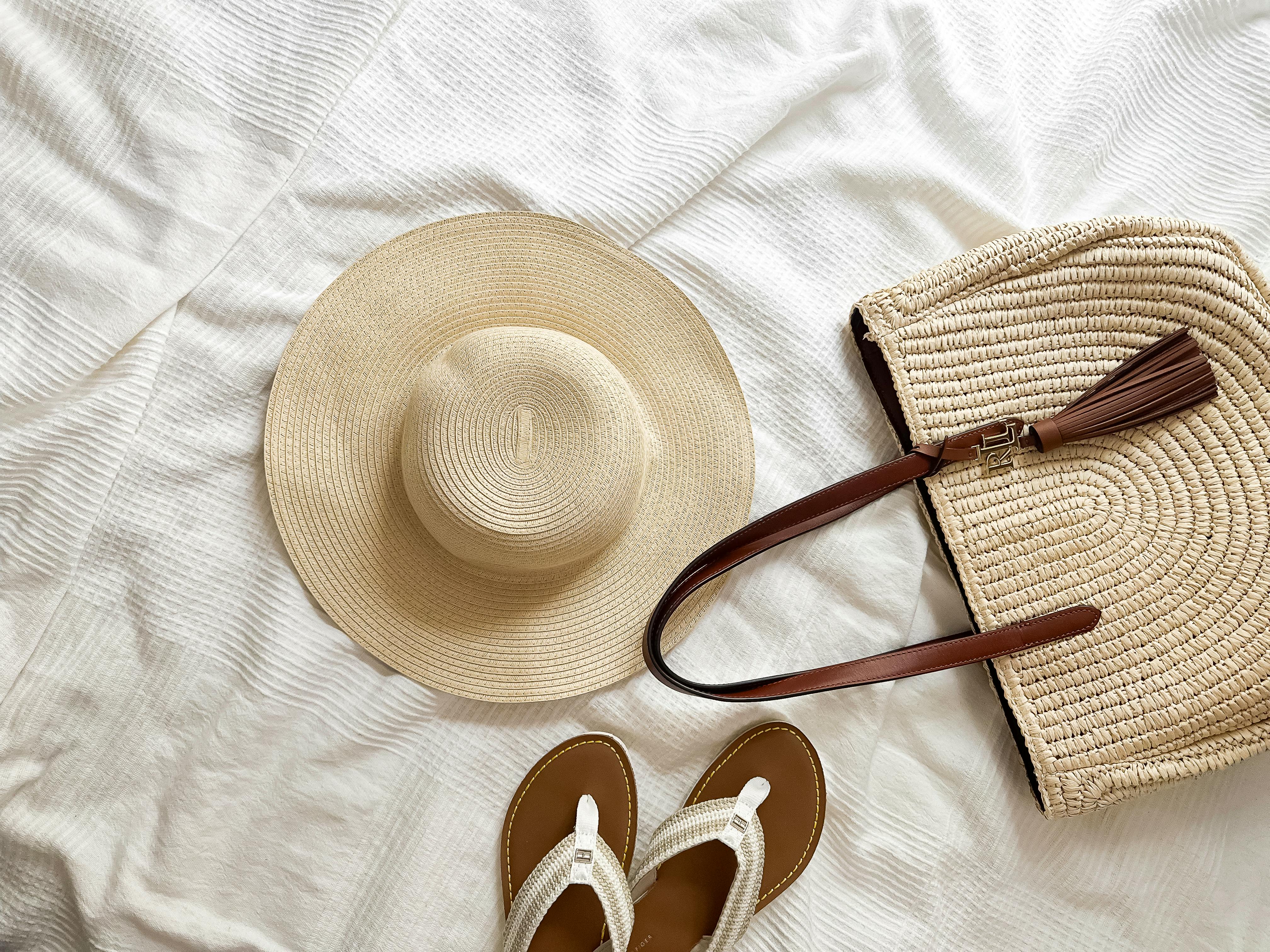 Stylish summer accessories including a sunhat, sandals, and a straw bag.