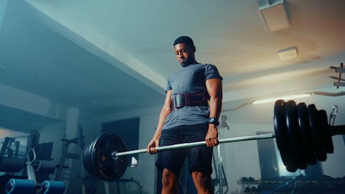 A man is lifting a barbell in a gym