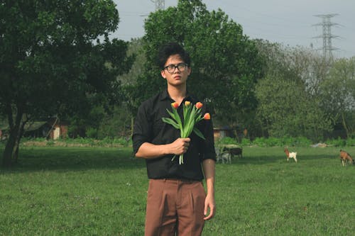 A man holding a bunch of flowers in a field