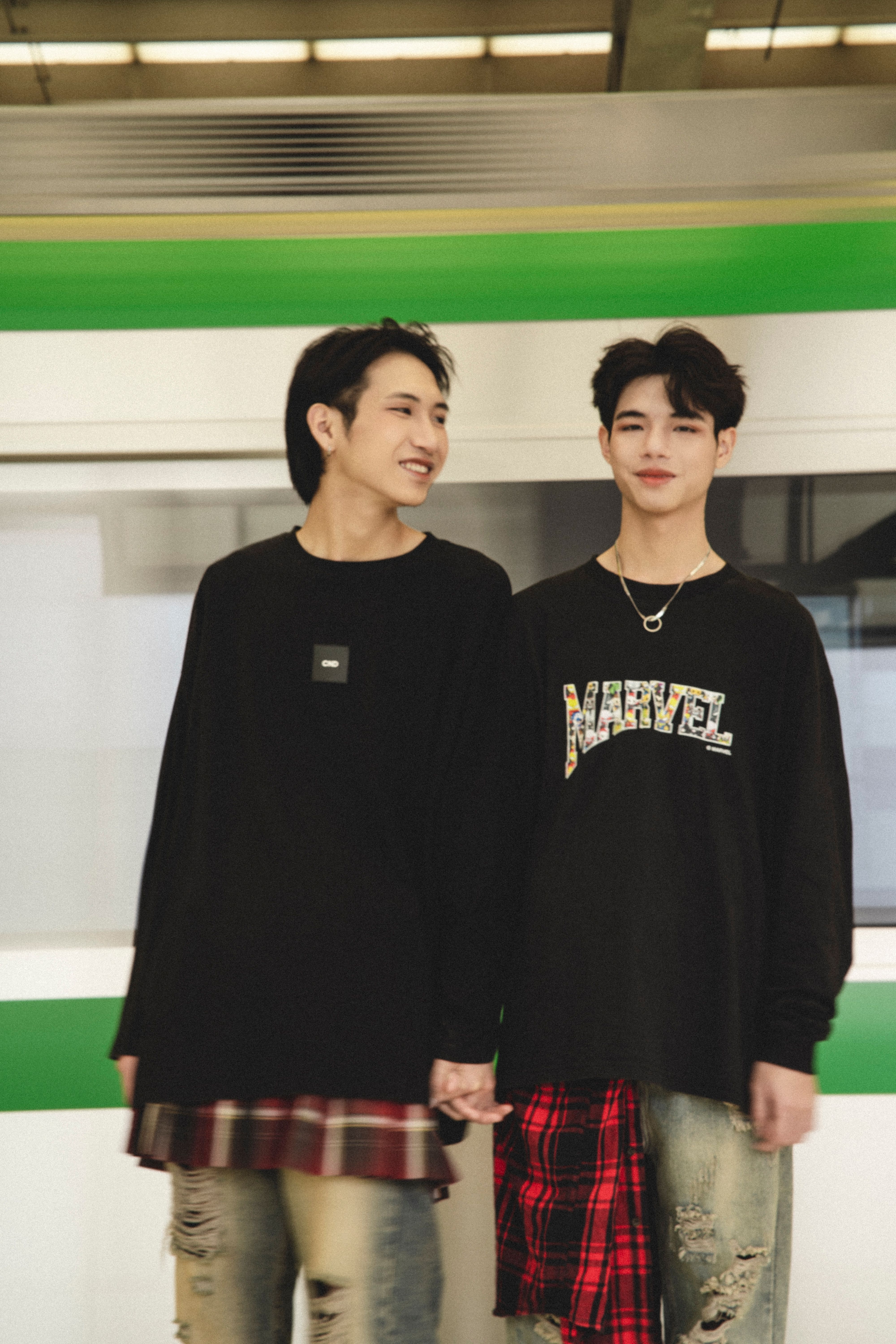 Young adults in stylish streetwear posing in an urban subway setting.