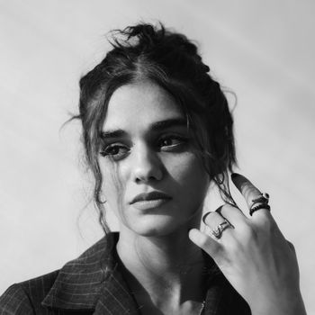 A studio shot of a woman adjusting her hair in a black and white portrait.