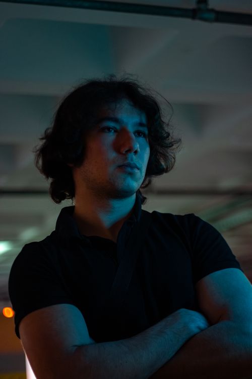 Free Cinematic portrait of a young man with curly hair in dramatic blue lighting. Stock Photo