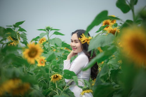 Woman Wearing White Long-sleeved Shirt Standing at Yellow Sunflower Field