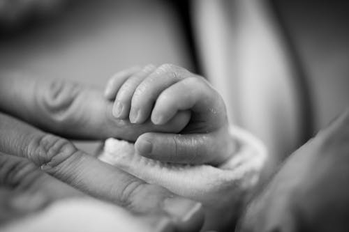 Fotografia Em Tons De Cinza De Um Bebê Segurando O Dedo