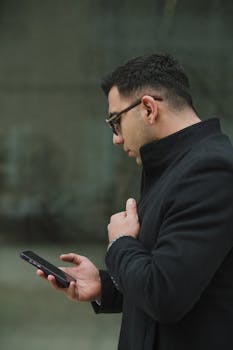 Portrait of a man in black coat using smartphone outdoors, modern lifestyle captured