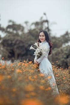 一位美丽的女子身着传统服装，在花田里手持花束