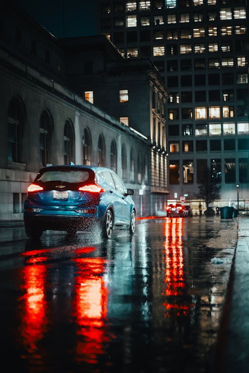 A car is driving down a street at night