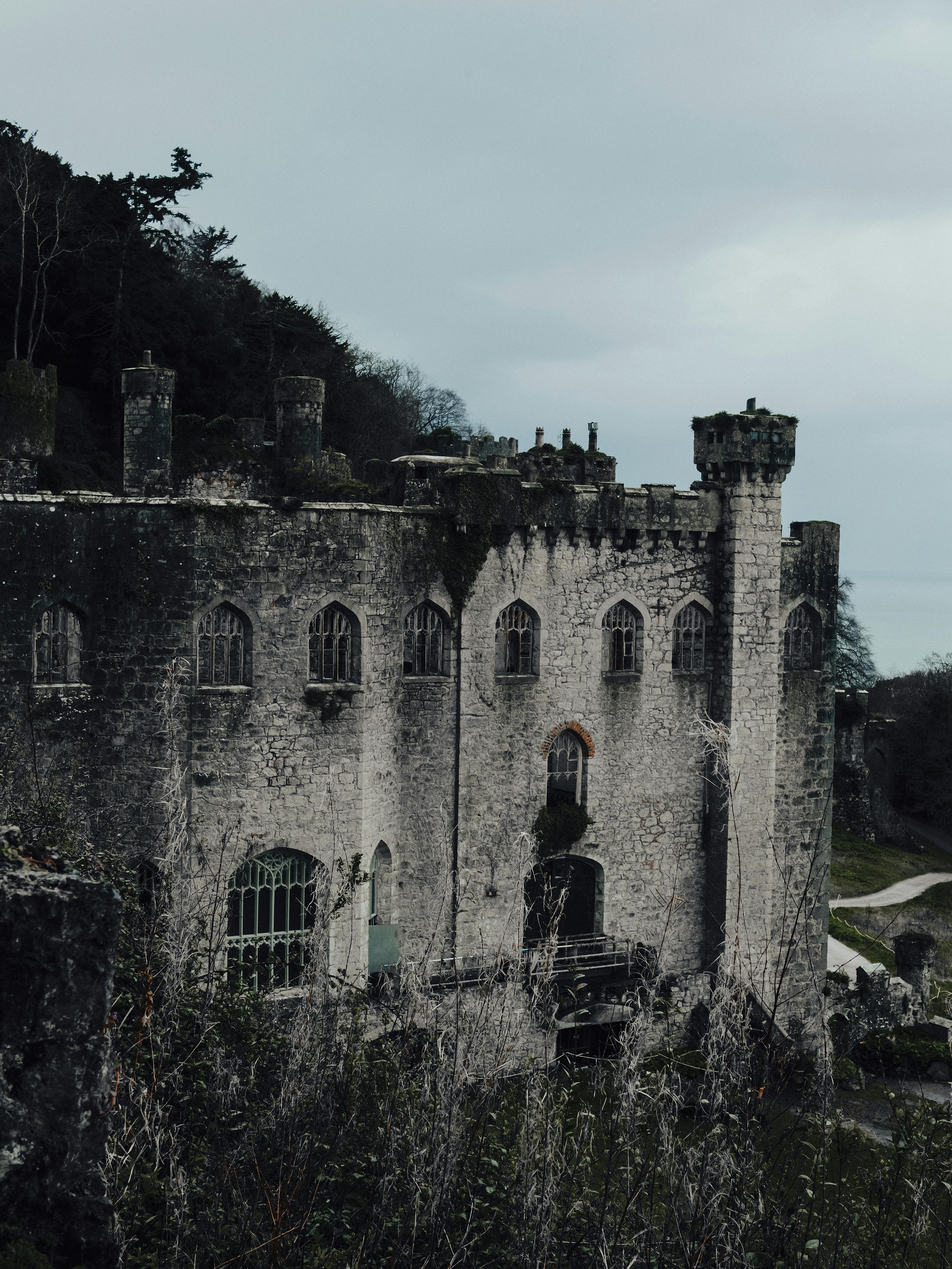 A dramatic view of a gothic-style castle in Abergele, Wales, surrounded by a moody landscape.