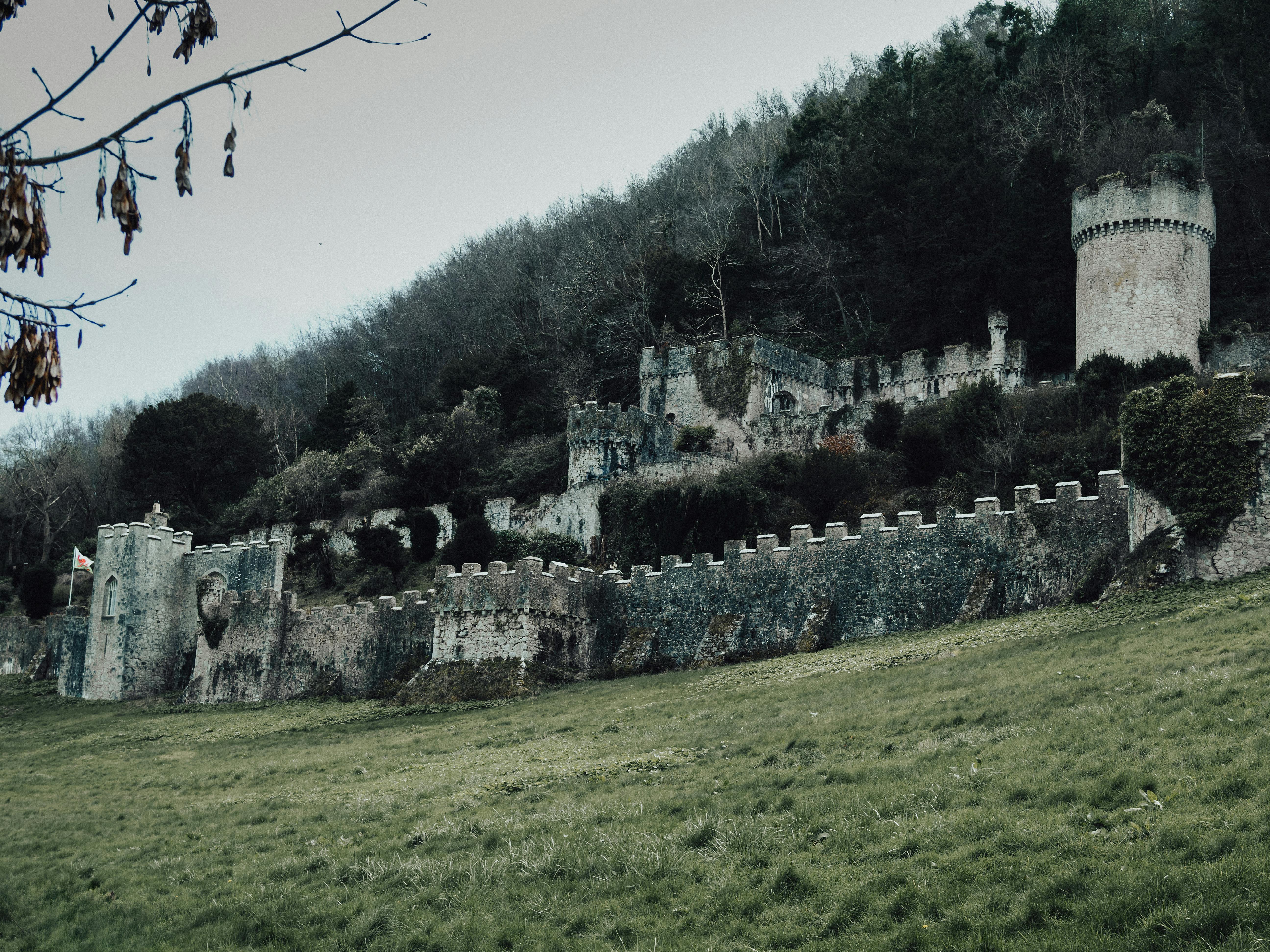 Explore the haunting ruins of the medieval Gwrych Castle set against a lush green hillside in Abergele, Wales.