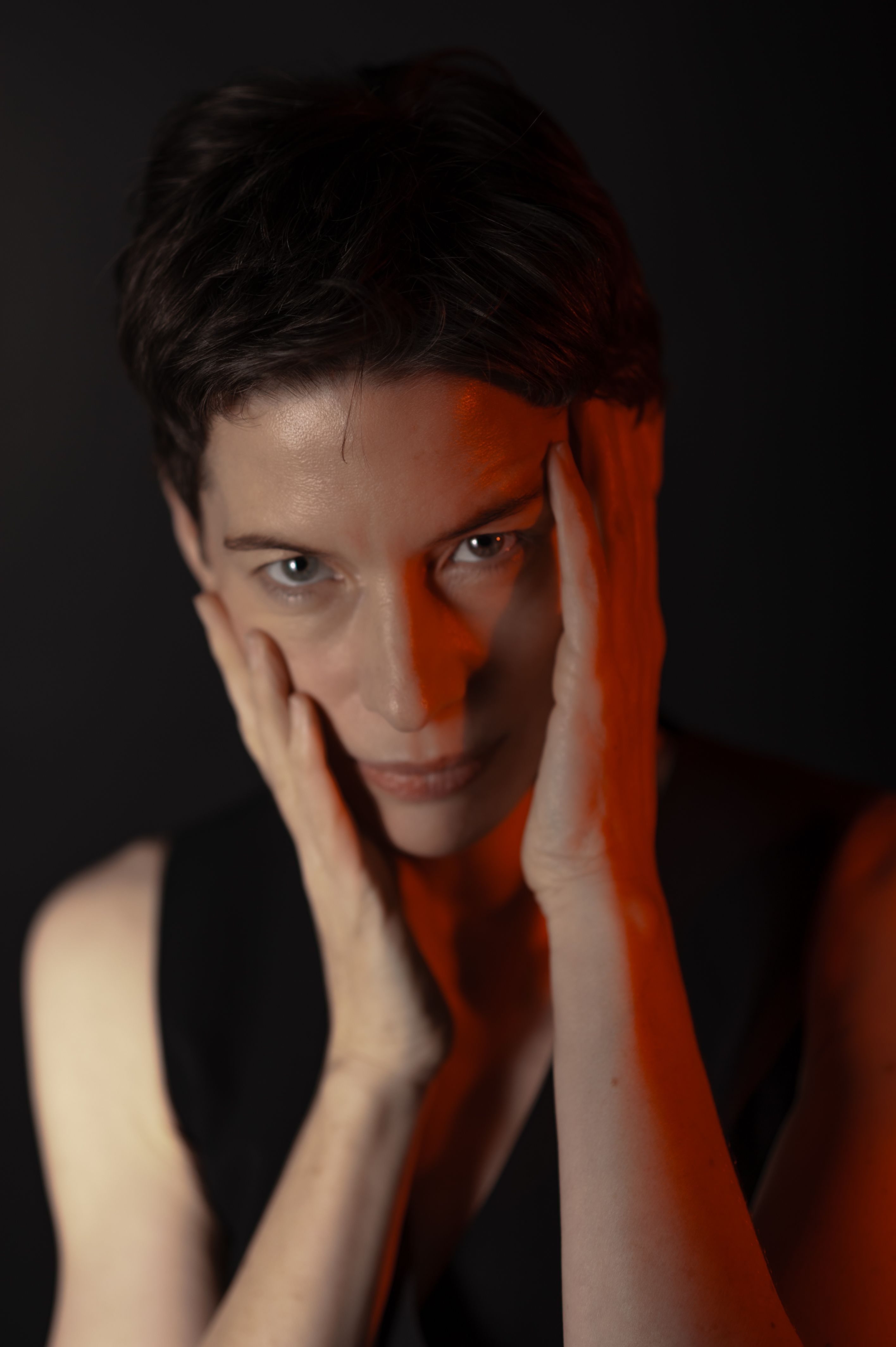 Captivating portrait of a woman with hands on face, dramatic lighting.