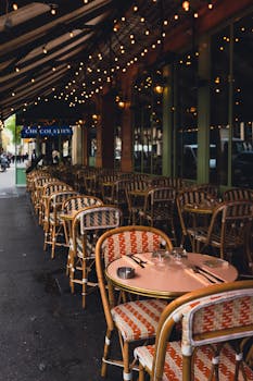 Outdoor restaurant with wicker chairs and warm lighting creates a cozy and inviting atmosphere on a city street.