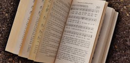 特写镜头展示了一本打开的书，书页上显示着音符和歌词，置于纹理表面之上