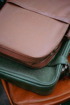 Close-up of a stack of vintage leather suitcases in various colors, showcasing timeless travel style.