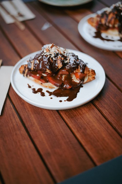 Free Delicious croissant topped with chocolate sauce, strawberries, and nuts on a white plate. Stock Photo