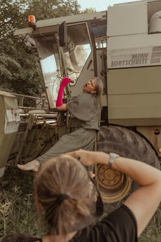 A unique fashion photography session featuring a woman posing with a combine harvester outdoors.