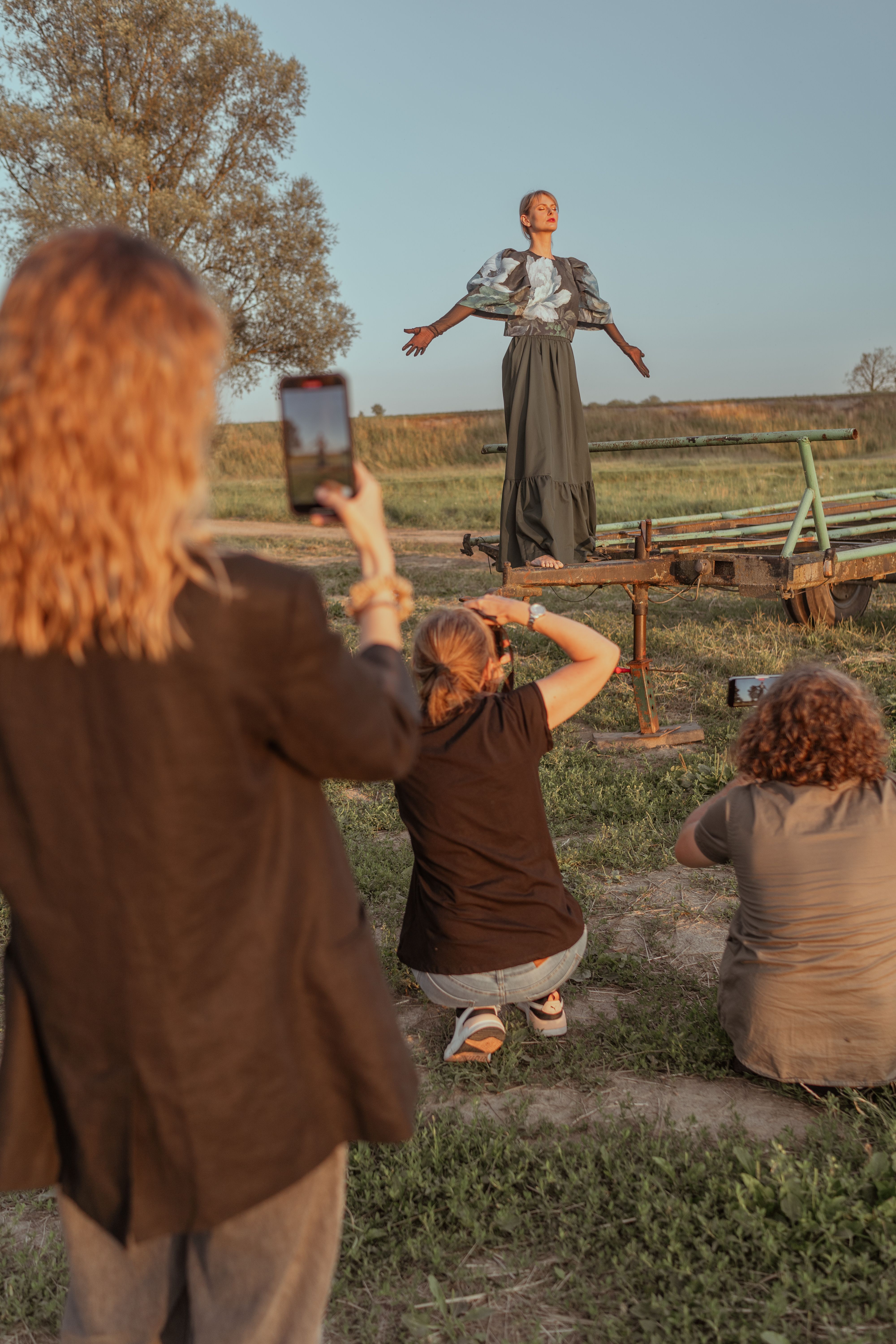 Woman posing on a trailer in rural Poland during a sunset fashion shoot.