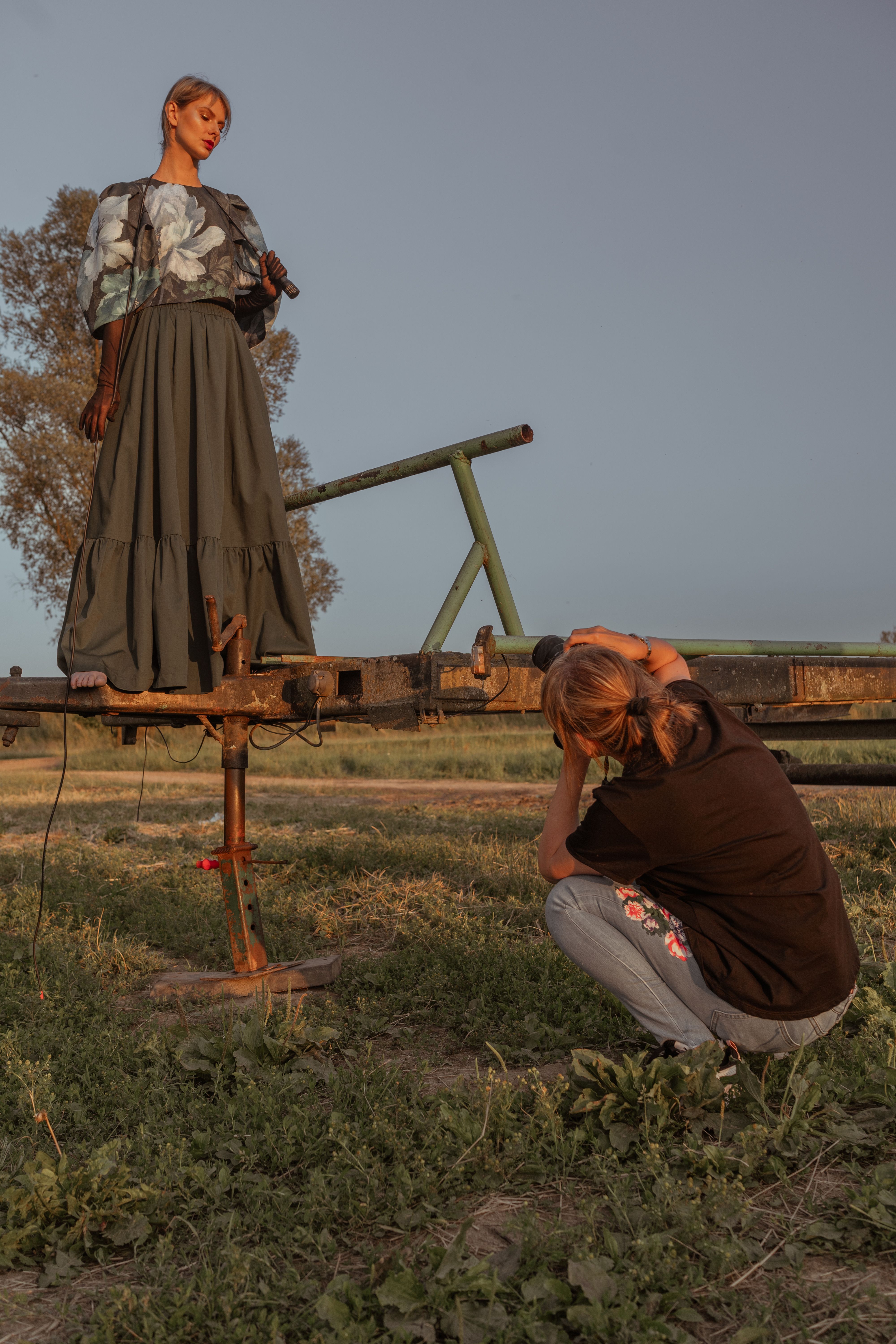 Artistic fashion photography session in rural Polish landscape during twilight.