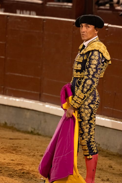 A bullfighter in a colorful outfit standing in front of a matador