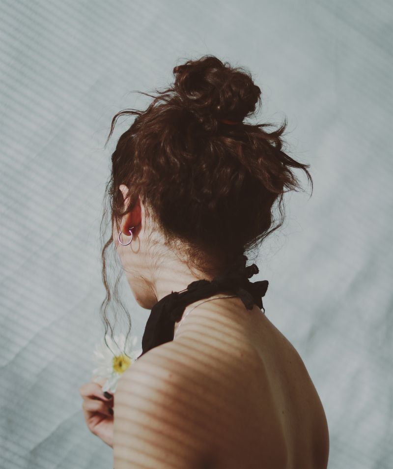 Brunette woman with an elegant updo holding a small flower