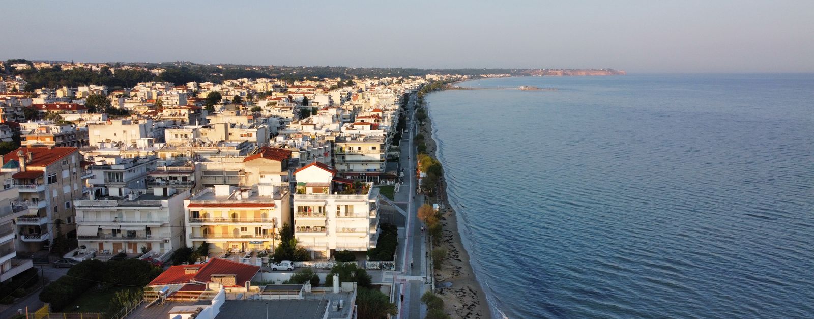 Aerial view of a coastal town with buildings and beach at sunset.