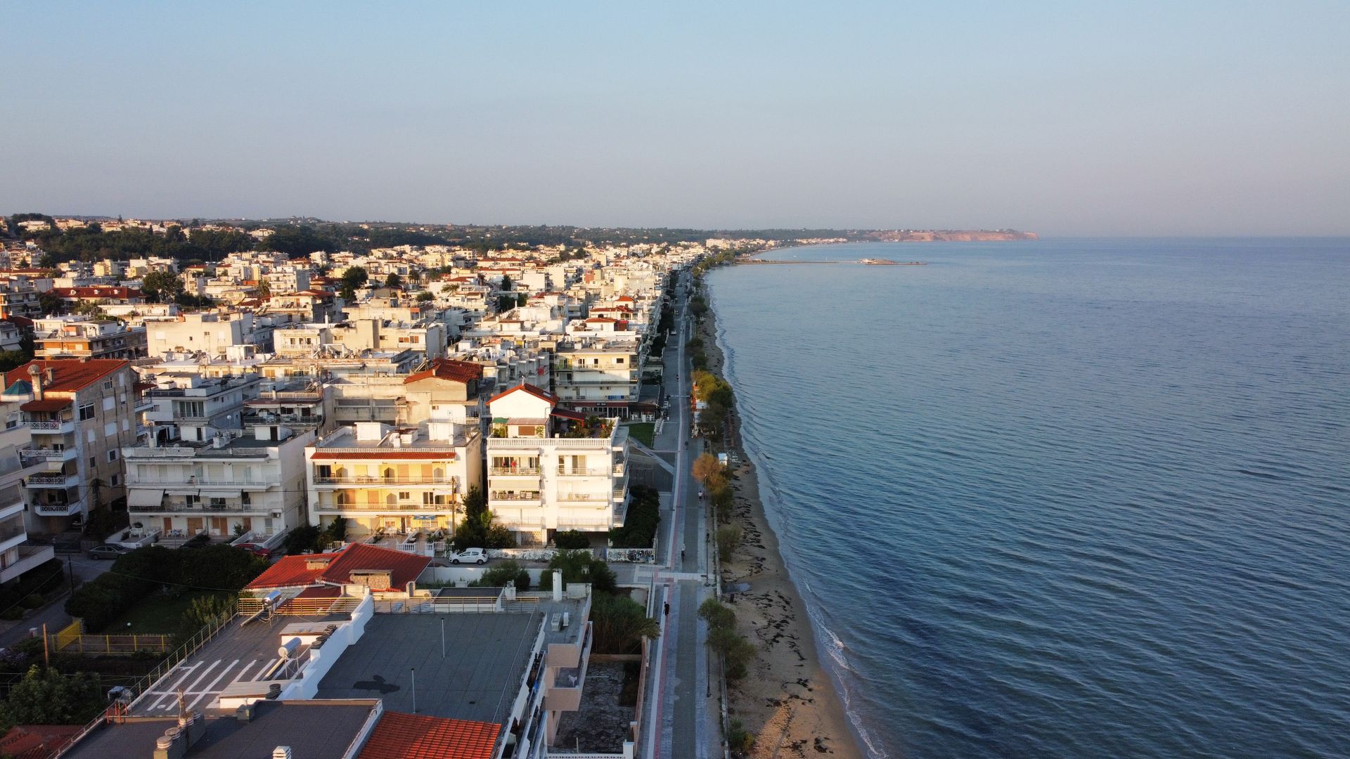 Aerial view of a coastal town with buildings and beach at sunset.