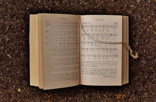 一本摊开的赞美诗书，泥土上铺着音符，以乐谱和歌词为特色