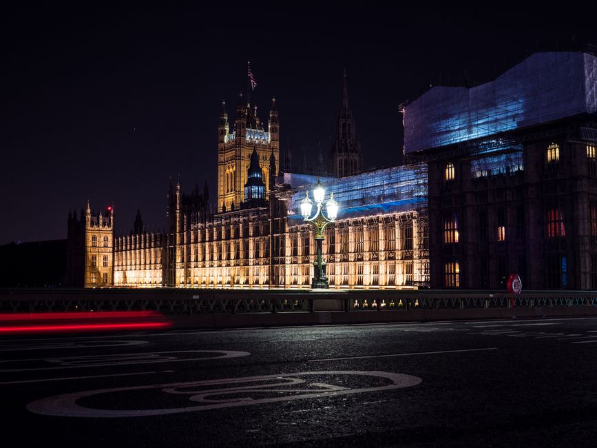Night view of the illuminated Houses of Parliament in London, showcasing iconic architecture.