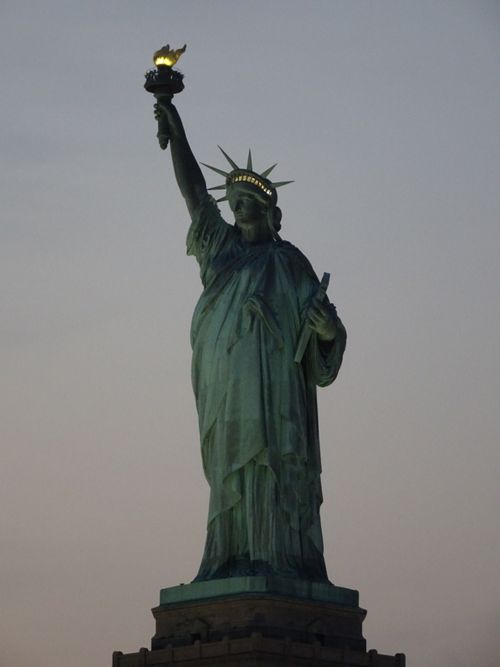 Free Iconic view of the Statue of Liberty during sunset in New York City, symbolizing freedom and democracy. Stock Photo