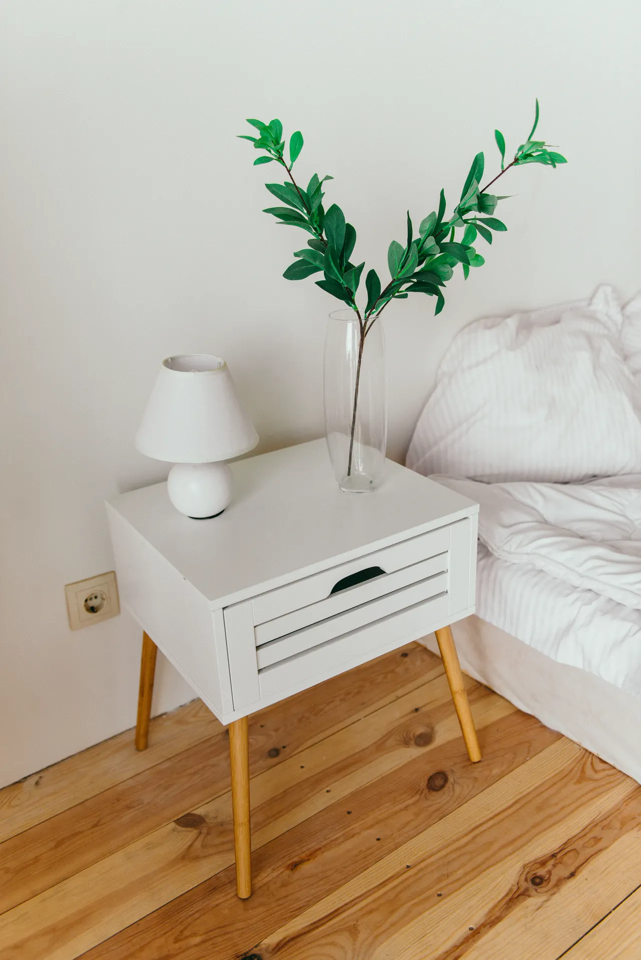 nightstand-decor-ideas-hero White table lamp and vase styled as nightstand decor in a modern bedroom