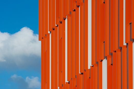 Striking modern architecture with vibrant orange panels against a clear blue sky in Rotterdam.