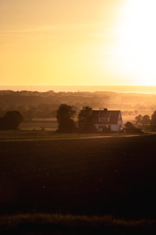 A farmhouse in the distance at sunset