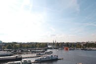 阿姆斯特丹运河上，船只点缀着风景，背景是树木和历史建筑