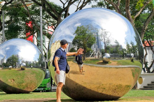 A man is standing in front of two large shiny balls
