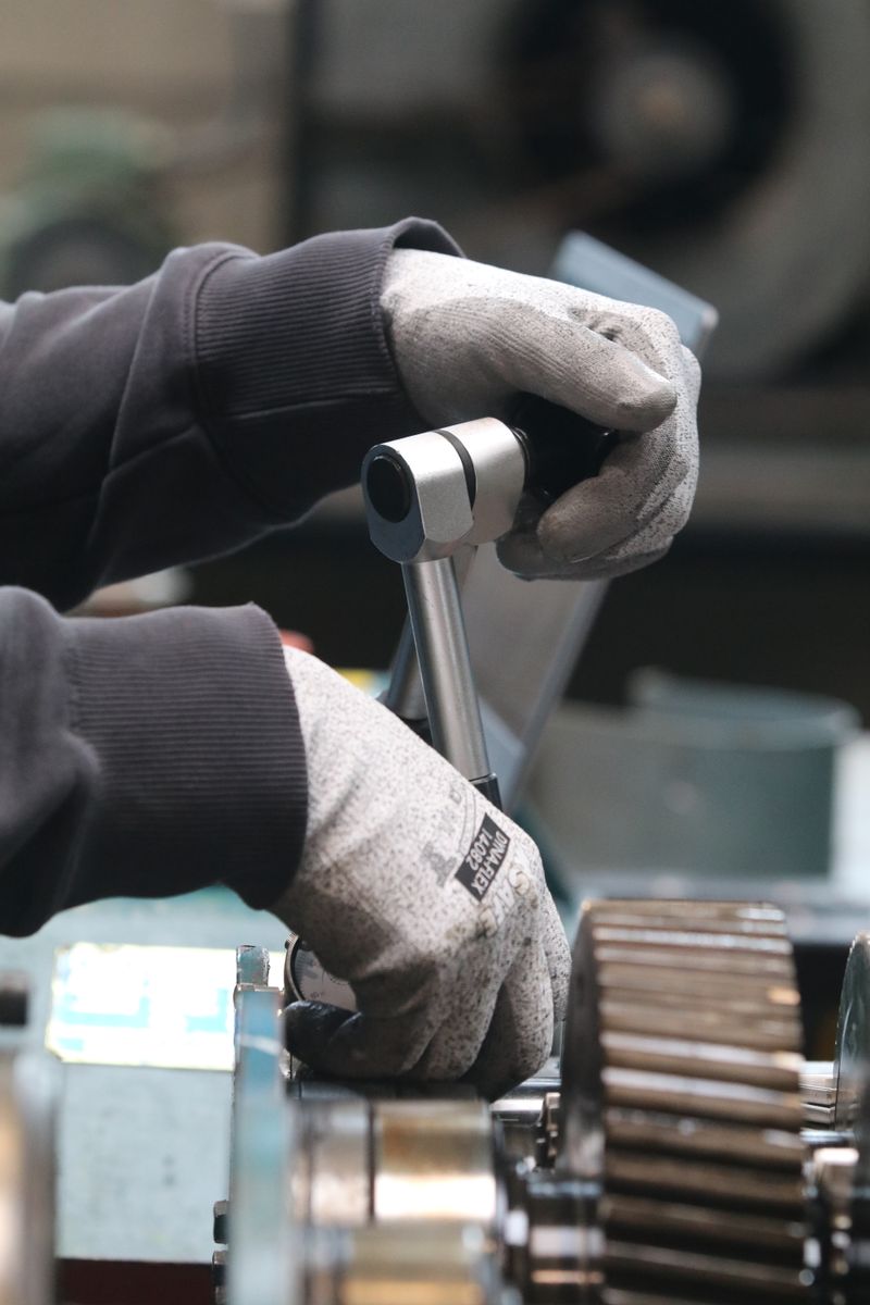 Close-up of mechanic using a wrench to adjust machinery, highlighting industrial work.