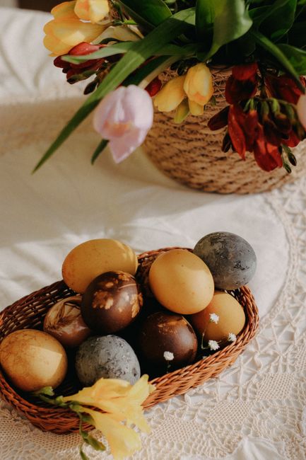 Colorful dyed Easter eggs in a basket with tulips, perfect for spring celebrations.