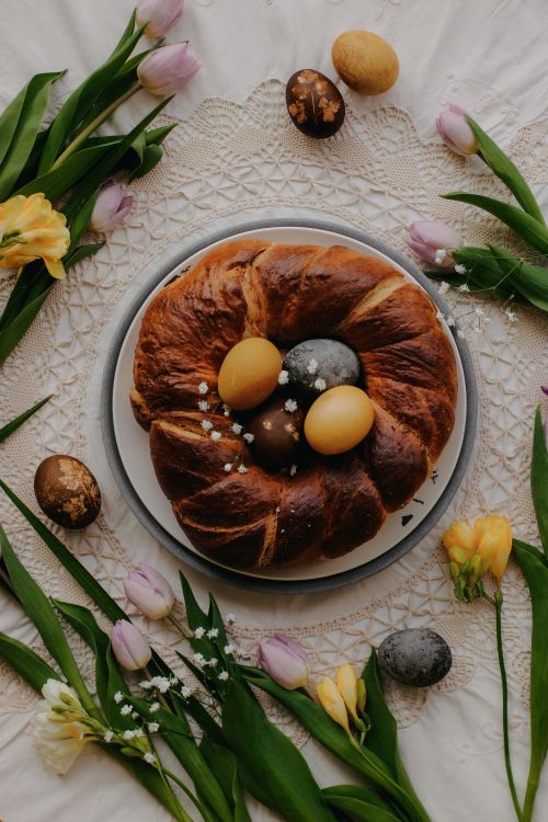 Free Festive Easter cake surrounded by colorful eggs and spring flowers, perfect for holiday celebrations. Stock Photo