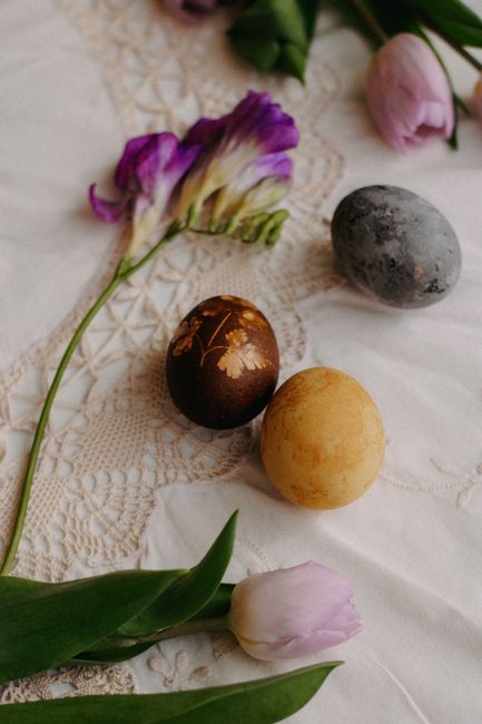 Decorative Easter eggs and flowers on lace tablecloth, ideal for spring themes.
