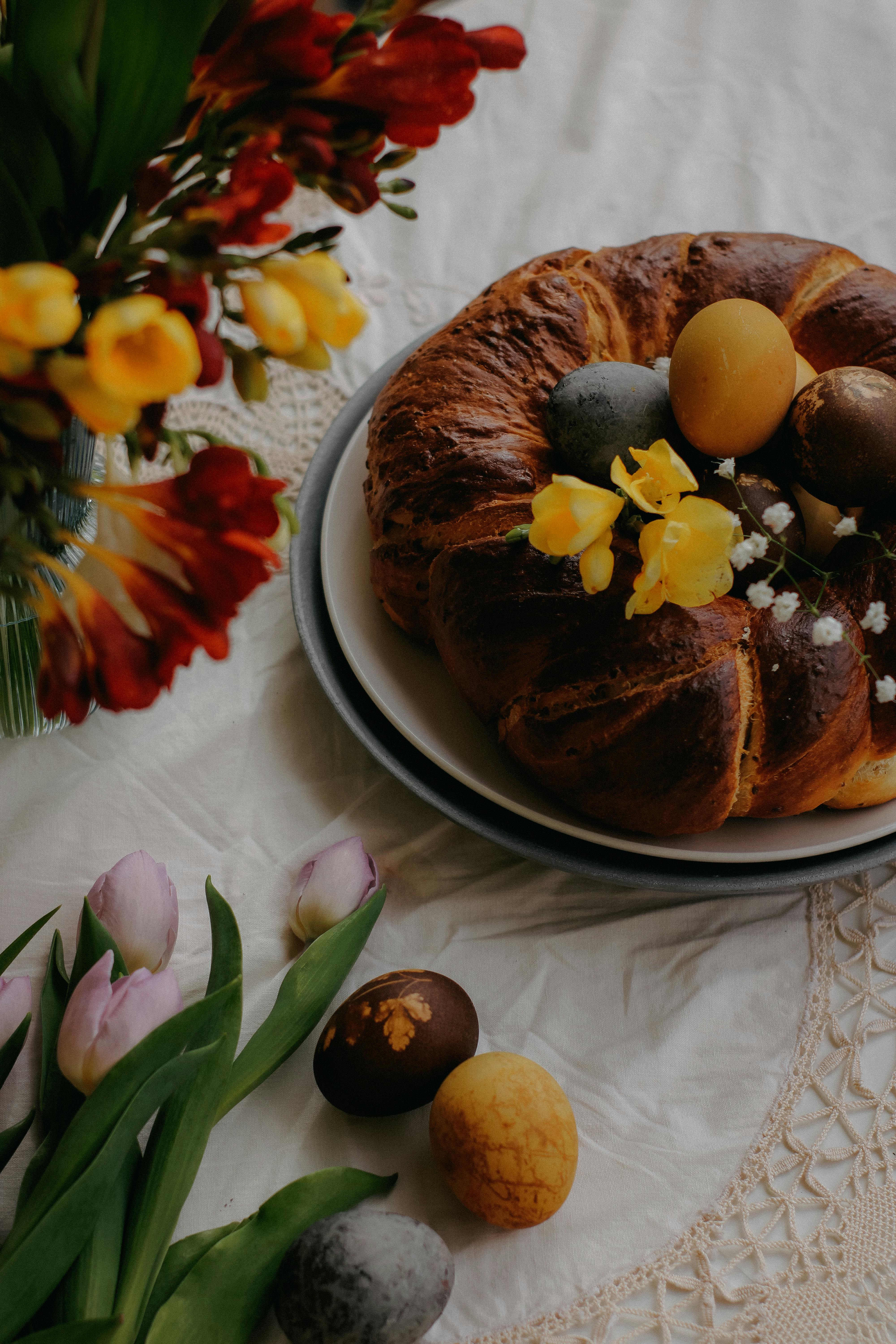 A vibrant Easter display with a cake, colorful eggs, and fresh flowers.