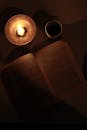 Top View of a Book Lying next to a Burning Candle