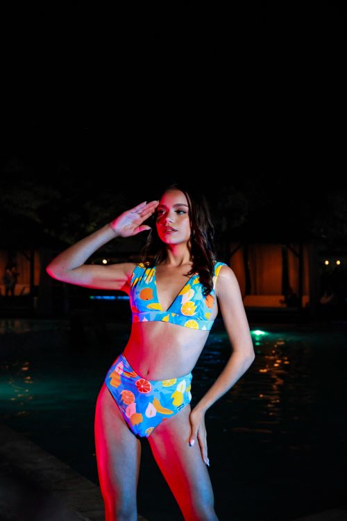Free Stylish woman posing in colorful swimwear by a pool at night. Stock Photo