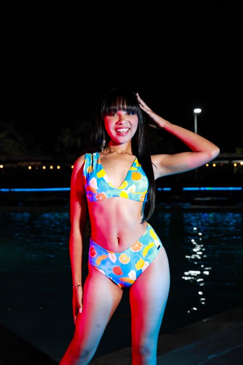 Free A woman in a colorful bikini poses confidently by the pool at night, smiling. Stock Photo