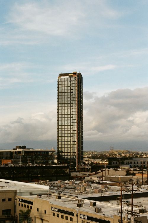 Free View of a tall skyscraper amidst urban Los Angeles with a cloudy sky backdrop. Stock Photo